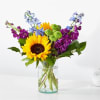 Sunflowers and purple-blue flowers in a clear glass vase