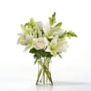 White lilies and roses arranged in a clear glass vase