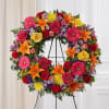 Standing wreath arrangement with red roses and carnations; orange Asiatic lilies and