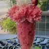 Milkshake-style floral arrangement with pink and white carnations, straws, and a polka dot ribbon butterfly.