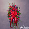Standing spray of red roses and purple flowers with a large red bow on an easel