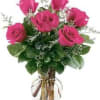 Clear glass vase of hot pink roses with white accent blooms