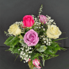 Small vase arrangement of cream, pink, and lavender roses with white filler flowers.