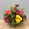 Mixed bouquet of yellow roses, purple daisies, and pink carnations in a white bowl vase