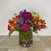 Colorful mixed bouquet in a clear glass vase with decorative stones