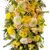 Tall yellow and white standing floral spray with roses, mums, and lilies on an easel