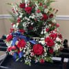 Standing red and white floral spray with matching wreath of roses and tulips and a blue ribbon.