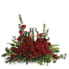 A bed of deep red roses cradles a silver-toned metal cremation urn