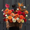 Vivid orange and deep red roses take center stage in this fall-inspired