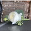 Small white ranunculus floral accent with berries and buds on a wet metal surface