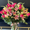 A soft and elegant vase arrangement featuring fresh lilies and roses in