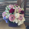 A lush, compact floral arrangement built around large pink and lavender-pink roses