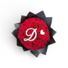 Round bouquet of red roses with white flowers forming a letter D and heart, wrapped in black paper.