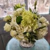 White roses and hydrangeas in a clear glass vase with white stones