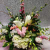 Low centerpiece of white calla lilies, hydrangeas, and pink roses with branches on a soft pink and silver backdrop