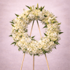 Large white floral wreath on a wooden easel against a soft neutral background