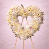 Large heart-shaped standing wreath of white and pale pink flowers on a wooden easel.