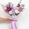 A front-facing bouquet with different tones of lilac, lavender, and purple, wrapped