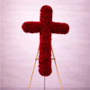 Standing cross of red roses on a wooden easel against a soft pink backdrop