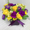 Low cube arrangement of yellow roses and daisies with purple carnations and asters in a purple vase with ribbon