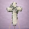 Standing cross-shaped spray of white roses on a wooden easel against a soft lavender background