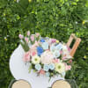 Pastel bouquet of roses, tulips, and peonies in a white cart