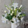 Tall white arrangement with lilies, calla lilies, roses, and orchids in a white vase