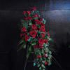 Tall standing spray of red roses arranged in a cascading shape on a black stand.