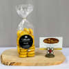 Bag of yellow emoji chocolates on a wood slab with a decorative business card holder