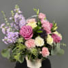 Basket arrangement of pink and cream roses with lavender stock and green thistle blooms