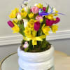 Bright arrangement of yellow daffodils and multicolor tulips in a white pot with decorative birds and butterfly