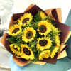 Bouquet of bright yellow sunflowers with greenery wrapped in brown and tan paper on a teal chair