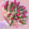 A lively cluster of hot pink tulips and soft cream-to-blush roses creates