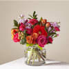 Bright mixed bouquet of pink and orange flowers in a clear glass cylinder vase