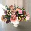 Compote arrangement of blush pink chrysanthemum and tan roses in a white pedestal vase