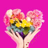 Heart-shaped bouquet of pink and yellow flowers held in two hands