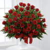 Large arrangement of red roses with red ribbon in a white pedestal vase