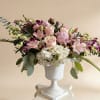 Low pink and white flower arrangement with roses, peonies and hydrangeas in a white urn-style vase