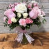 Pink and white roses with pink carnations in a clear glass vase tied with a pink ribbon bow