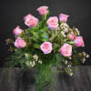 Arrangement of pink roses with small white blossoms in a clear glass vase