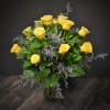 Arrangement of yellow roses with soft purple filler in a clear glass vase