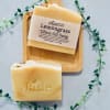 Two beige lemongrass olive oil soap bars on a wooden board with a trailing vine accent.