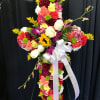 Standing cross of mixed bright flowers with roses and sunflower, white bow, and 'Beloved Brother' ribbon.