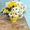 Yellow and white daisy bouquet in a smiley-face mug