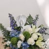 White angel figurine surrounded by blue and white flowers in a low arrangement