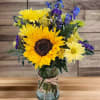Sunflower bouquet in a glass vase with yellow and purple flowers
