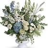 White and blue floral arrangement in a white pedestal vase