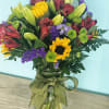 Mixed bouquet in a glass vase with yellow lilies and purple flowers