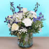 White and blue floral arrangement in a clear glass vase
