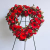 Heart-shaped red floral wreath on a black stand